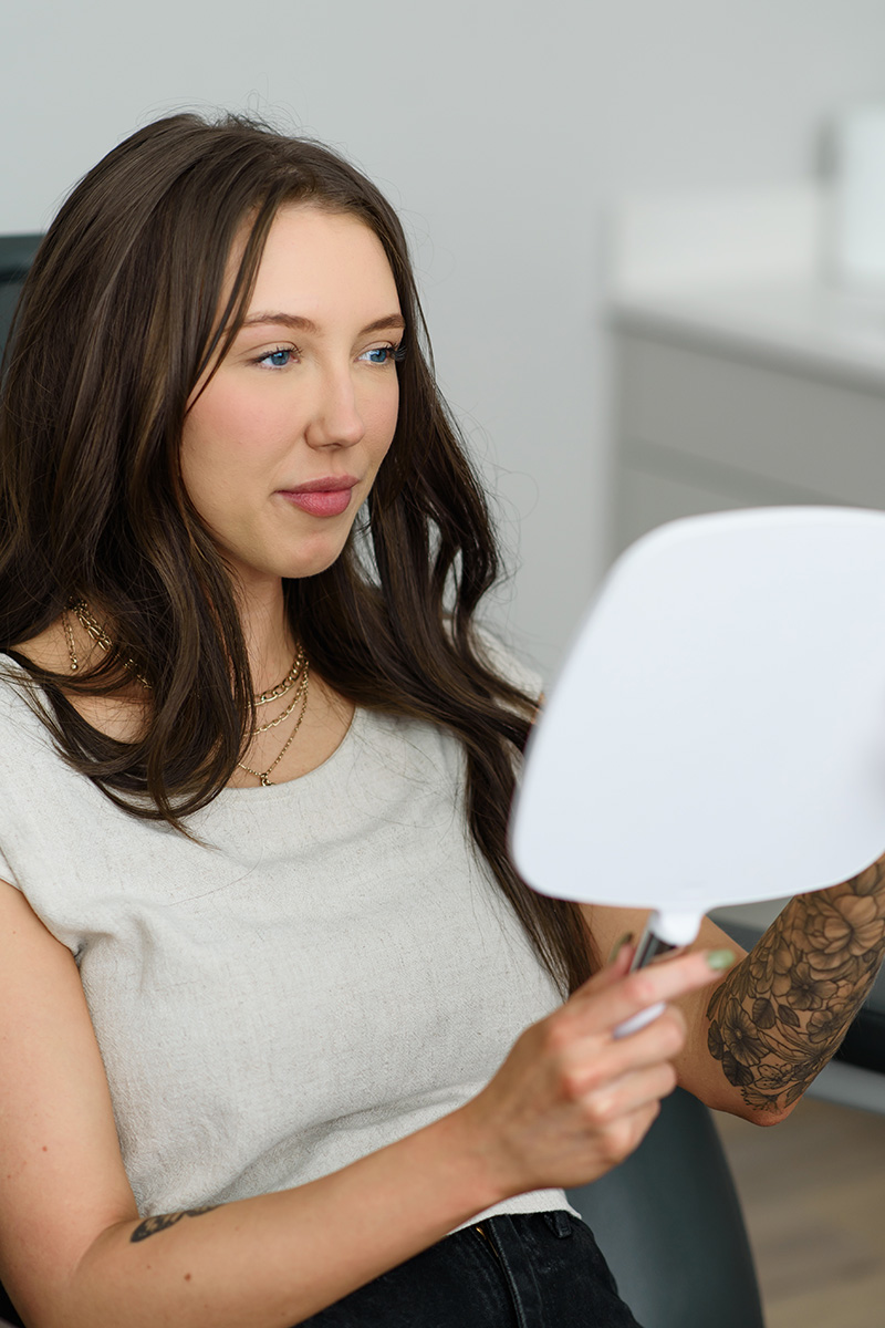 an Evolve Aesthetics & Wellness client holding a mirror during a consultation