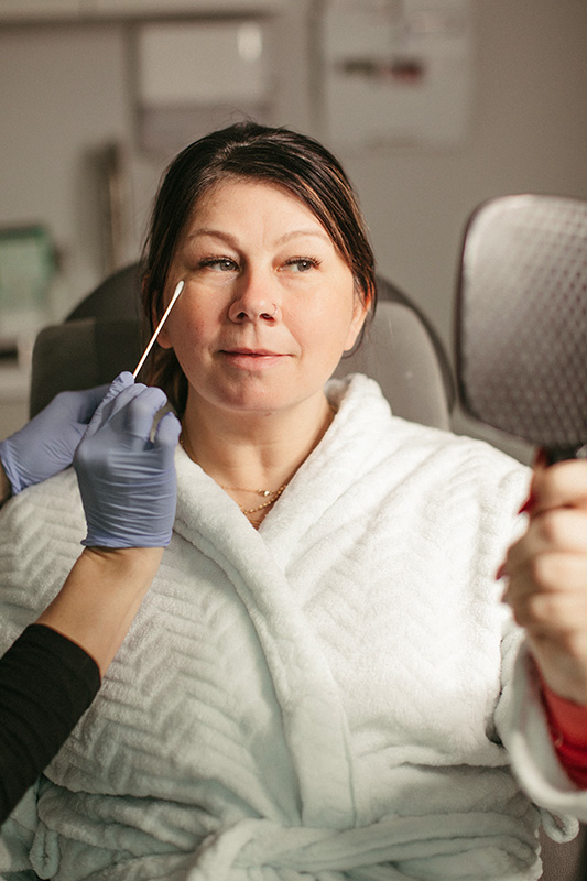 an Evolve Aesthetics & Wellness patient holding a mirror during a consultation